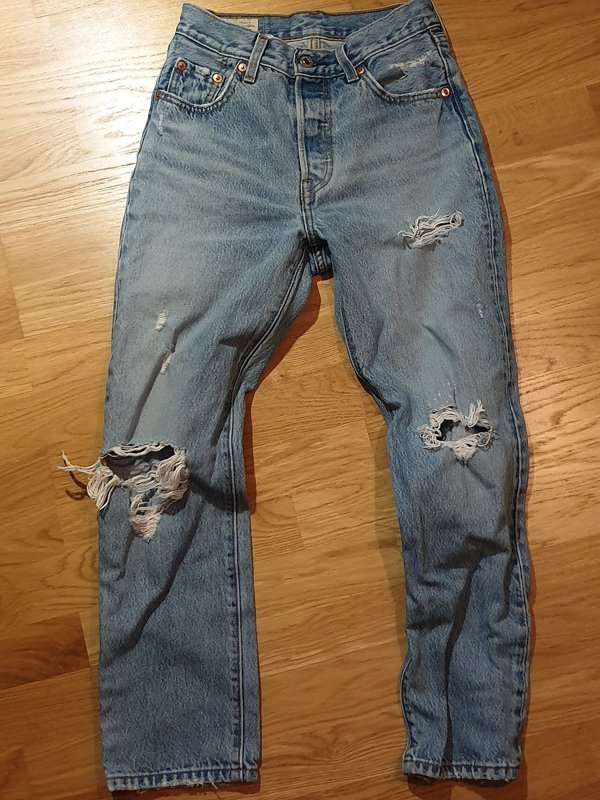 Light-wash Levi's 501 jeans with ripped knees and thigh